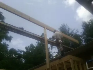 Carpenter setting a ridge beam over a new addition frame — Ice Dam Removal by Roofing Brothers in Willow Creek