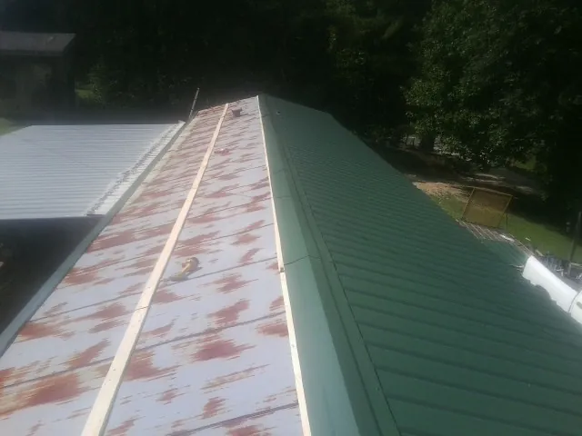 Old rusted panels beside newly installed green metal roofing — Wind Damage Roof Repair by Roofing Brothers in Willow Creek
