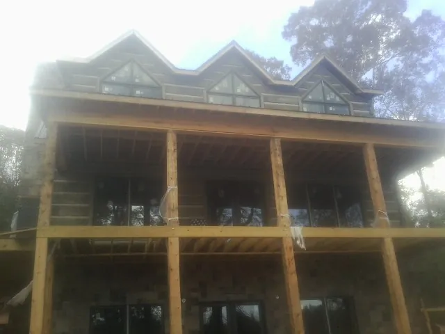 Dormers and porch framing on a large log home under construction — Roof Coating work by our crew in Willow Creek