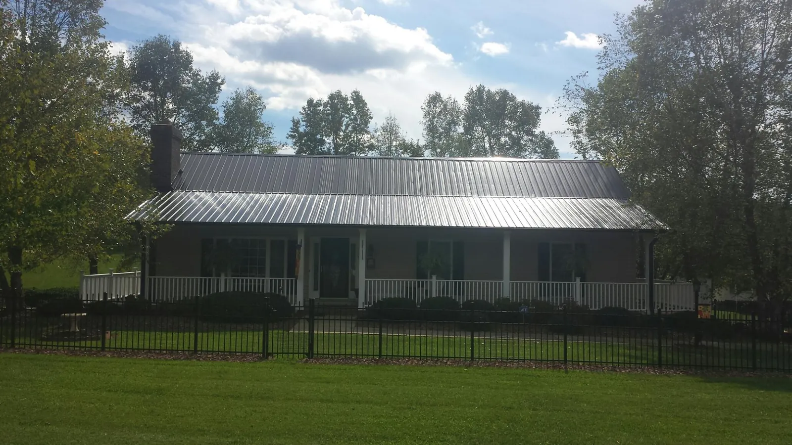 Gray metal roof on a brick ranch with a full width front porch — Gutter Guard Installation work by our crew in Willow Creek