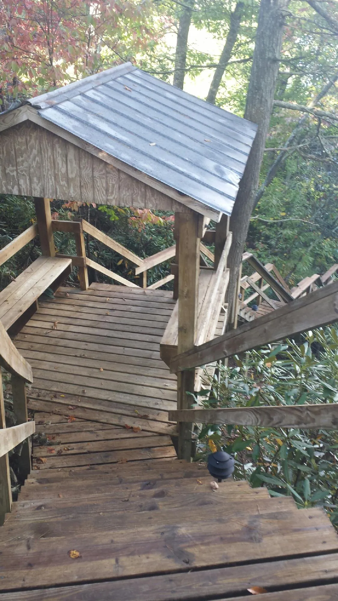 Metal roofed shelter over wooden steps on a wooded walkway — Skylight Repair & Installation work by our crew in Willow Creek