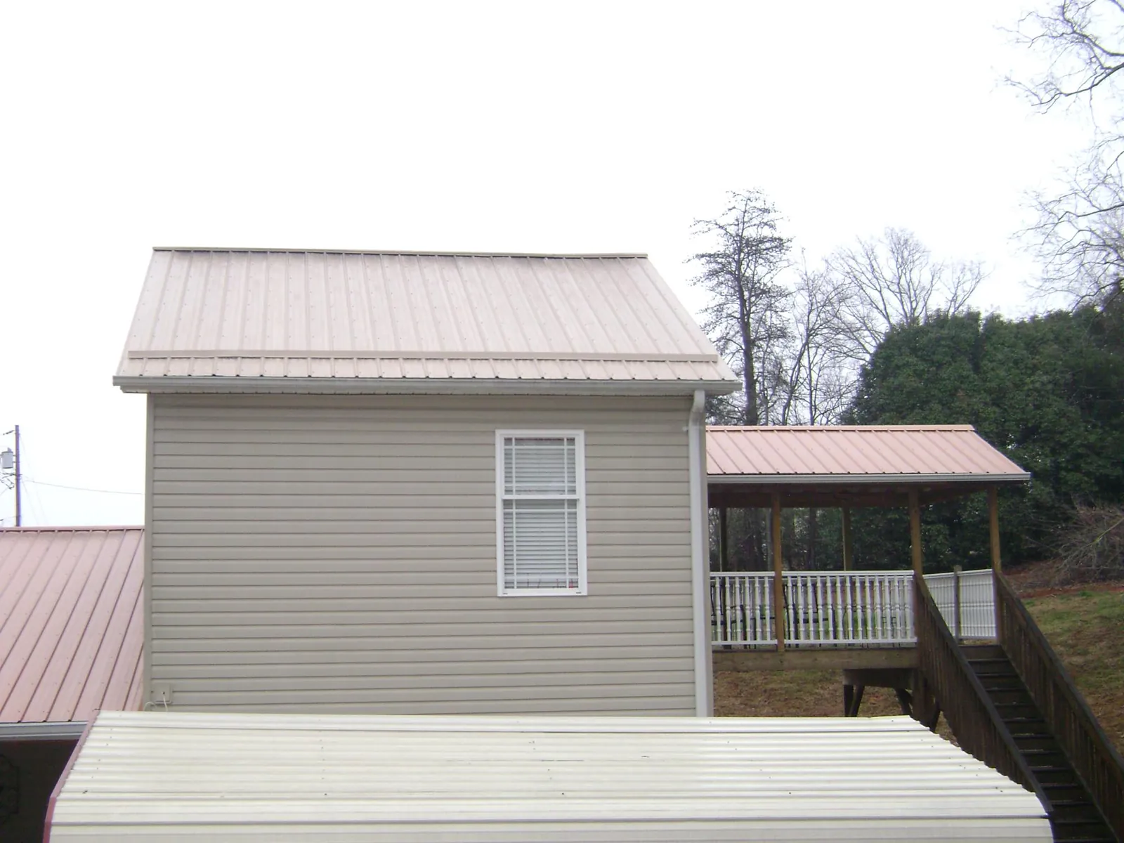 Tan metal roofs on a two story addition and attached porch, from a Roof Replacement job in Willow Creek