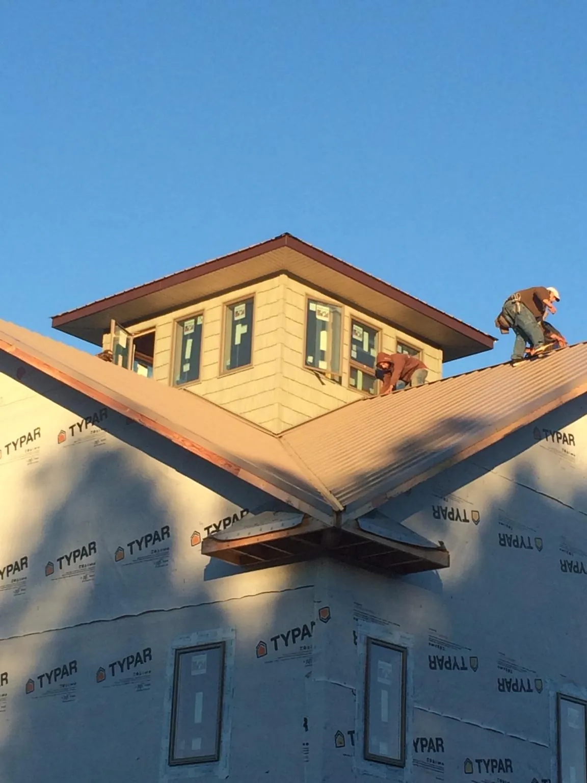 Roofers working around a rooftop cupola on a new metal roof at sunset — Roof Waterproofing in Willow Creek by Roofing Brothers